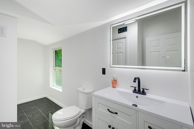 bathroom with visible vents, vanity, toilet, baseboards, and vaulted ceiling