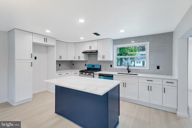 kitchen with a sink, tasteful backsplash, under cabinet range hood, and stainless steel range with gas cooktop