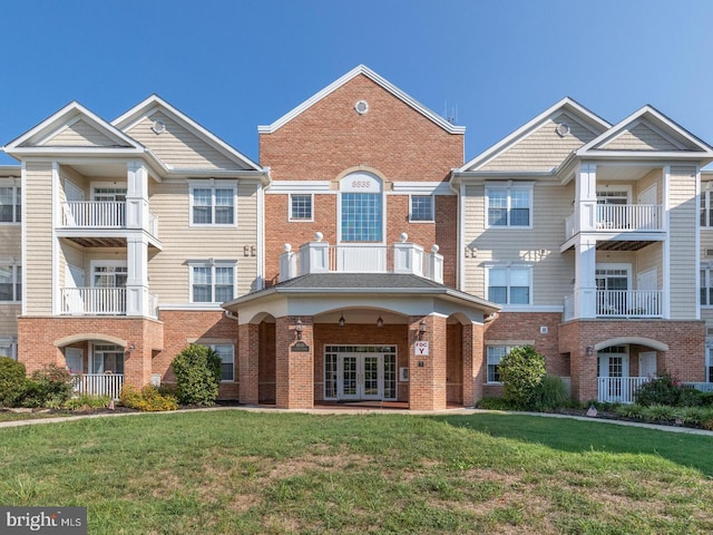 view of property with french doors, brick siding, and a front yard