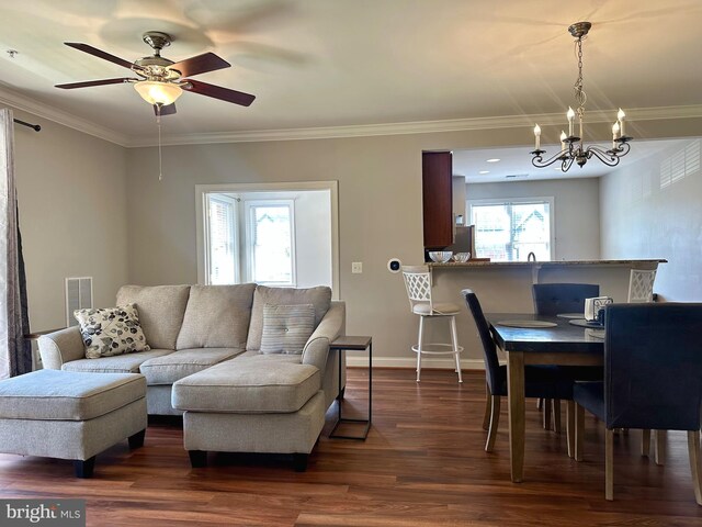 living room featuring visible vents, dark wood-style flooring, crown molding, and ceiling fan with notable chandelier