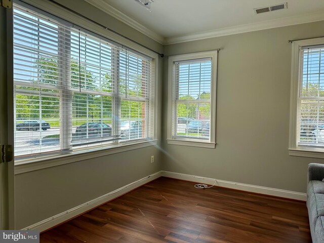 unfurnished room with visible vents, ornamental molding, baseboards, and dark wood-style floors