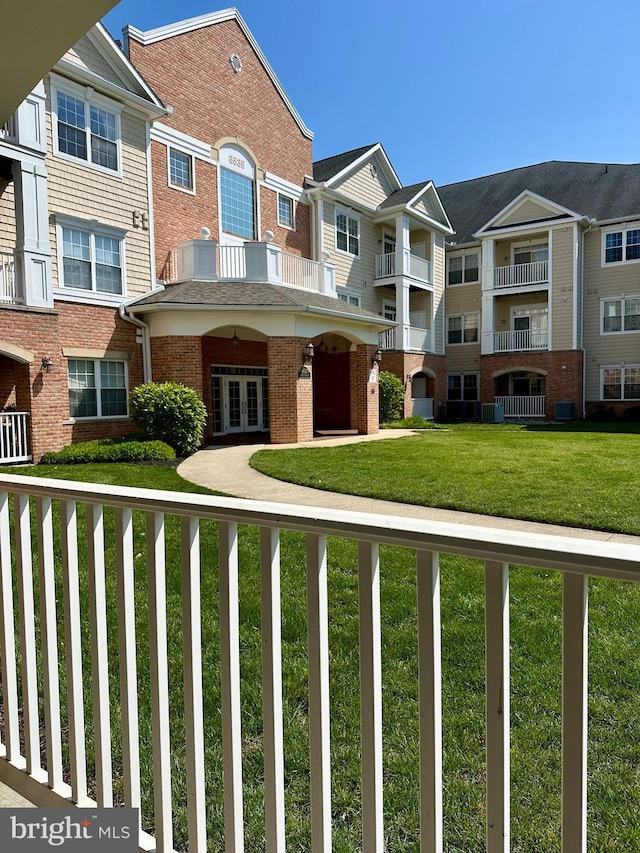 view of front facade with brick siding, a residential view, french doors, and a front lawn