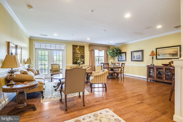 living area with visible vents, crown molding, baseboards, light wood-style floors, and recessed lighting