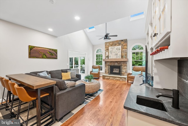 723 Ann Dr, Kennett Square, PA 19348 - living area with light wood-type flooring, a fireplace, a ceiling fan, a skylight, and high vaulted ceiling