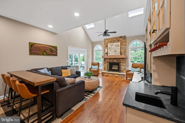 723 Ann Dr, Kennett Square, PA 19348 - living room with a skylight, a stone fireplace, light wood finished floors, ceiling fan, and high vaulted ceiling