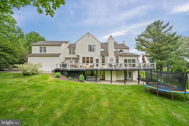723 Ann Dr, Kennett Square, PA 19348 - rear view of house with a trampoline, a wooden deck, stucco siding, and a yard