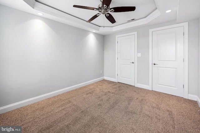unfurnished bedroom featuring visible vents, baseboards, recessed lighting, a tray ceiling, and carpet