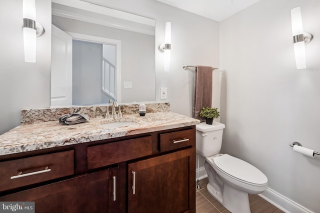 half bathroom with baseboards, vanity, and toilet