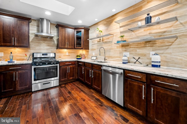 kitchen with decorative backsplash, wall chimney range hood, a sink, appliances with stainless steel finishes, and a skylight