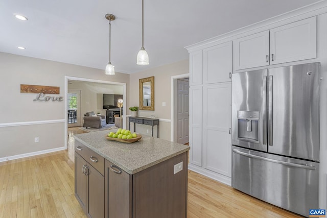 kitchen with stainless steel refrigerator with ice dispenser, pendant lighting, a center island, white cabinets, and light wood-style floors