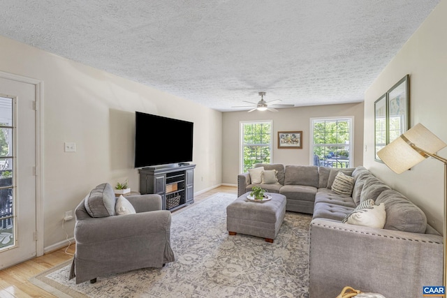 living area with baseboards, a ceiling fan, a textured ceiling, and wood finished floors