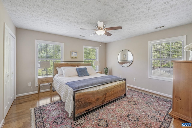 bedroom with visible vents, a textured ceiling, baseboards, and light wood-type flooring