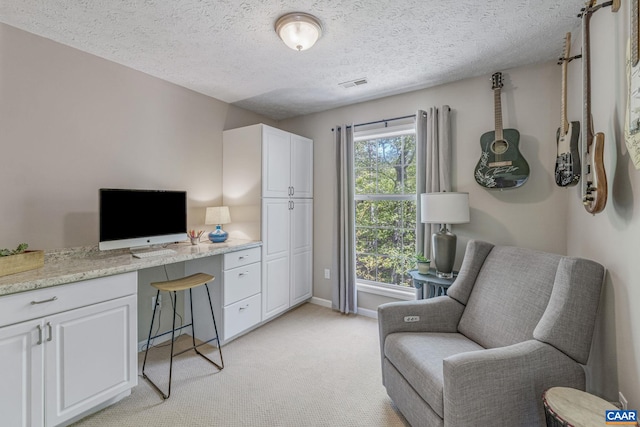 office space with baseboards, light carpet, a textured ceiling, and visible vents
