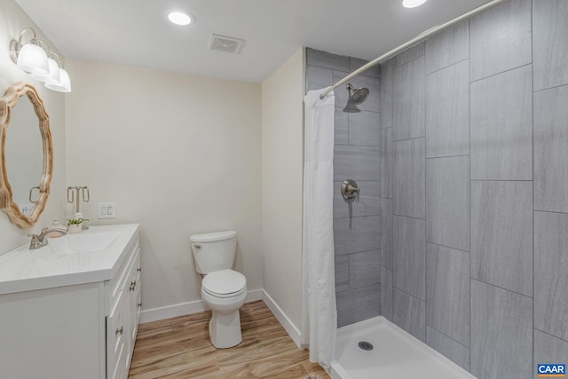 full bath featuring a tile shower, toilet, wood finished floors, and visible vents