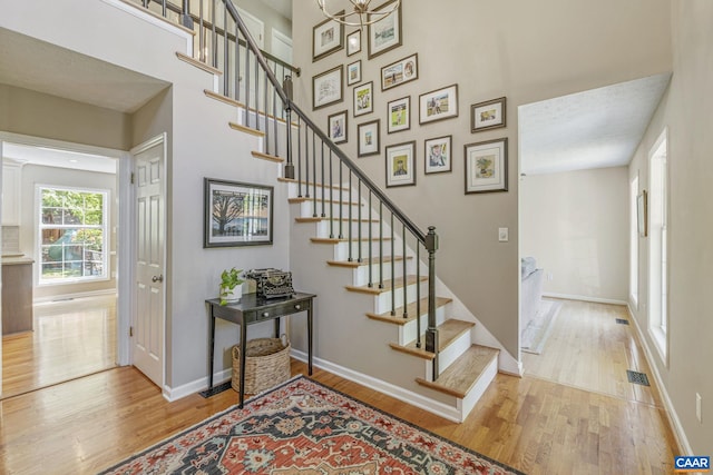 stairs with baseboards, wood finished floors, and a towering ceiling