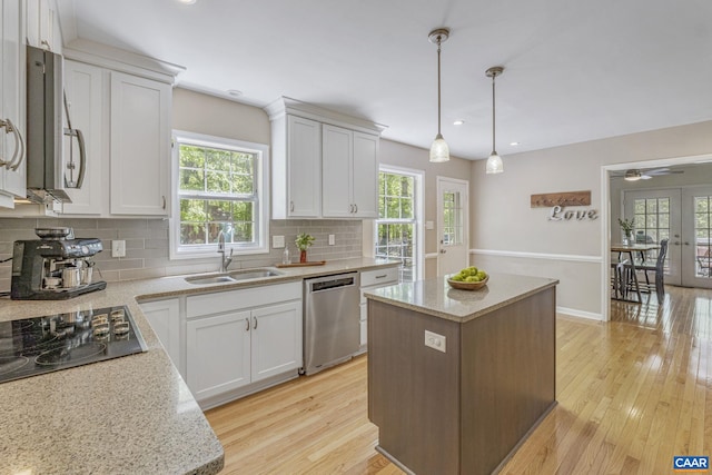 kitchen with a sink, stainless steel dishwasher, backsplash, and a healthy amount of sunlight