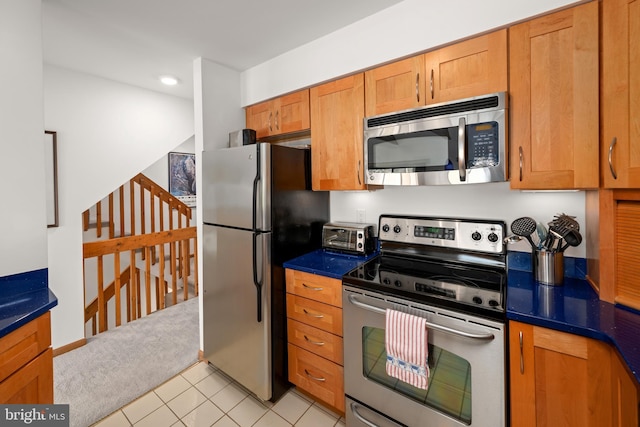 39947 Narrows Rd Unit 13, Fenwick Island, DE 19944 - kitchen with dark countertops, appliances with stainless steel finishes, brown cabinetry, and light tile patterned floors