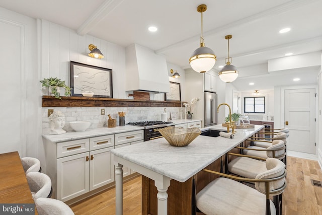 213 Morris St, Philadelphia, PA 19148 - kitchen featuring decorative backsplash, beam ceiling, a sink, premium range hood, and light wood-style floors