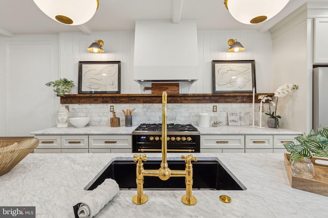 213 Morris St, Philadelphia, PA 19148 - kitchen with range with two ovens, light stone counters, custom exhaust hood, and tasteful backsplash