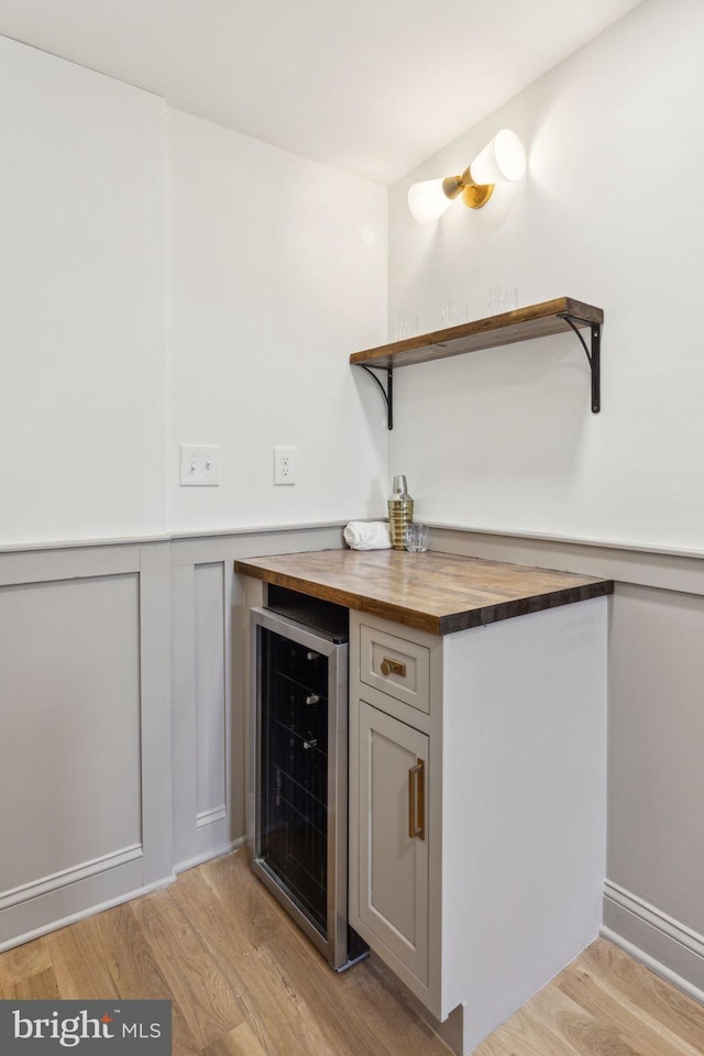213 Morris St, Philadelphia, PA 19148 - bar with wainscoting, a bar, light wood finished floors, beverage cooler, and a decorative wall