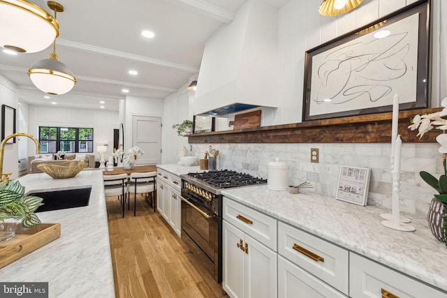 213 Morris St, Philadelphia, PA 19148 - kitchen featuring white cabinets, a sink, double oven range, light wood-type flooring, and tasteful backsplash
