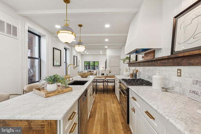 213 Morris St, Philadelphia, PA 19148 - kitchen with backsplash, appliances with stainless steel finishes, a sink, light wood-style floors, and white cabinetry