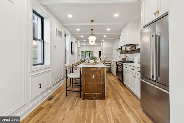 213 Morris St, Philadelphia, PA 19148 - kitchen featuring white cabinets, high quality appliances, a kitchen bar, visible vents, and custom exhaust hood