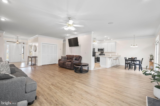living room featuring ornamental molding, light wood-style floors, baseboards, recessed lighting, and ceiling fan with notable chandelier