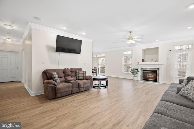 living area featuring crown molding, baseboards, and light wood-type flooring