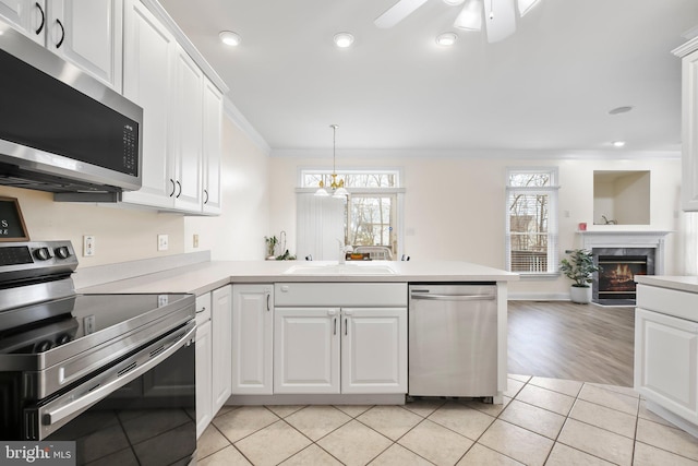 kitchen featuring crown molding, a sink, light countertops, ceiling fan with notable chandelier, and stainless steel appliances