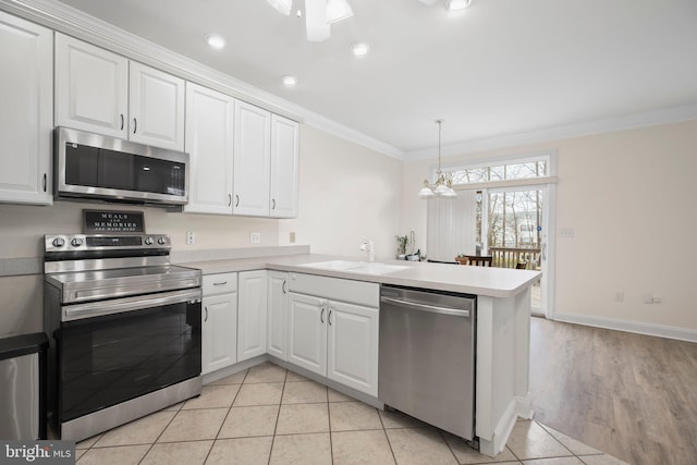 kitchen with ornamental molding, a peninsula, white cabinets, a sink, and appliances with stainless steel finishes