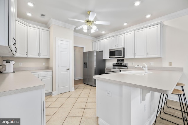 kitchen featuring crown molding, ceiling fan, appliances with stainless steel finishes, a sink, and a peninsula