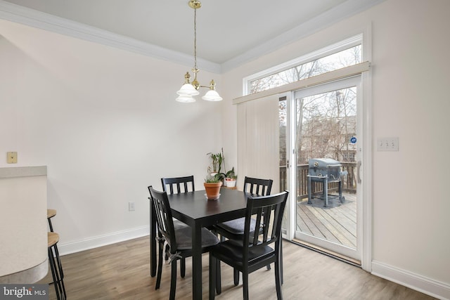 dining space featuring crown molding, baseboards, wood finished floors, and an inviting chandelier