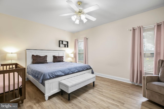 bedroom with a ceiling fan, baseboards, and light wood-type flooring