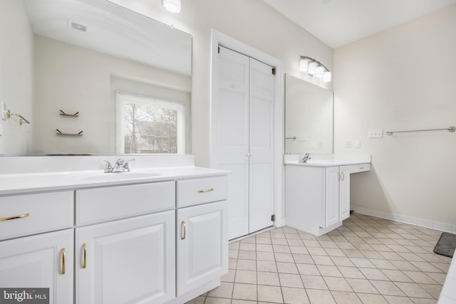 bathroom featuring a sink, baseboards, tile patterned flooring, and two vanities