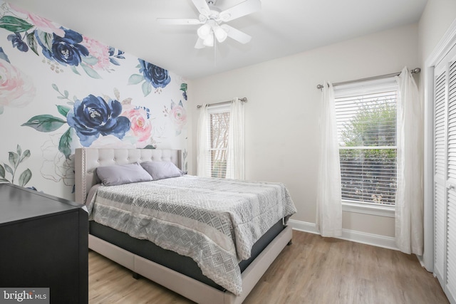bedroom featuring a ceiling fan, baseboards, wood finished floors, and a closet