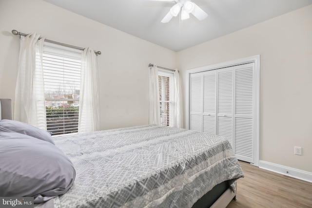 bedroom with baseboards, ceiling fan, wood finished floors, and a closet