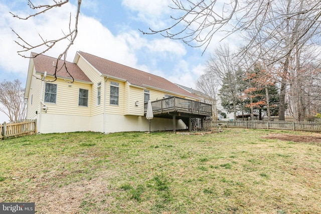 back of house with a yard, a wooden deck, a fenced backyard, and roof with shingles