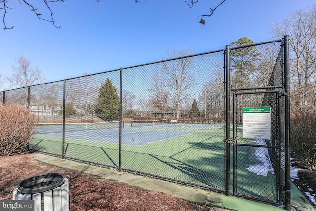 view of tennis court featuring fence and a gate