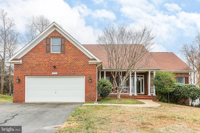 view of front of house with a porch, driveway, a front yard, a garage, and brick siding