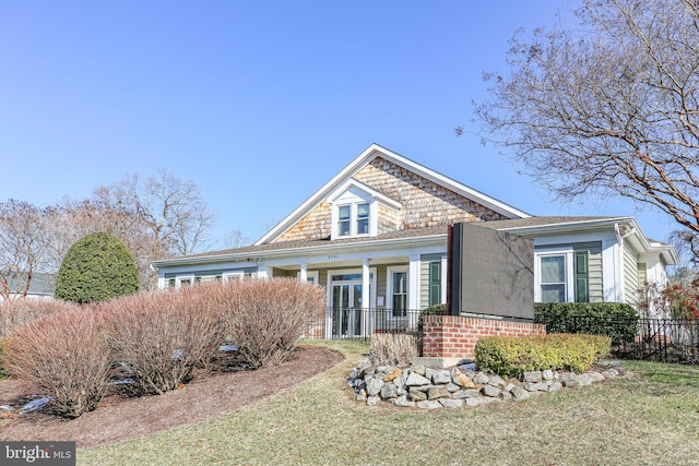 view of front of property with a porch, a front lawn, fence, and brick siding