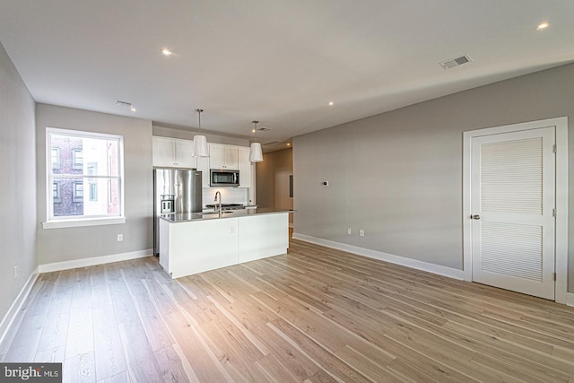 5412 Chancellor St, Philadelphia, PA 19139 - kitchen featuring visible vents, appliances with stainless steel finishes, light wood-type flooring, baseboards, and white cabinetry