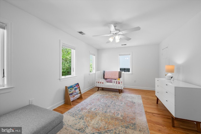 bedroom with visible vents, light wood-style flooring, ceiling fan, and baseboards