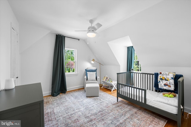 bedroom with baseboards, wood finished floors, vaulted ceiling, and multiple windows