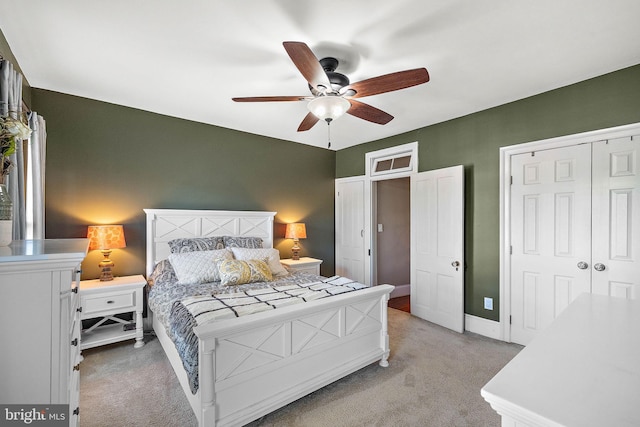 bedroom with ceiling fan, light colored carpet, baseboards, and a closet