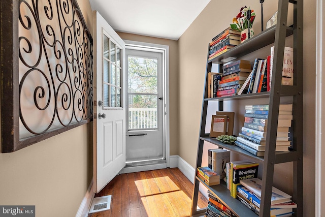 doorway to outside with visible vents, wood-type flooring, and baseboards