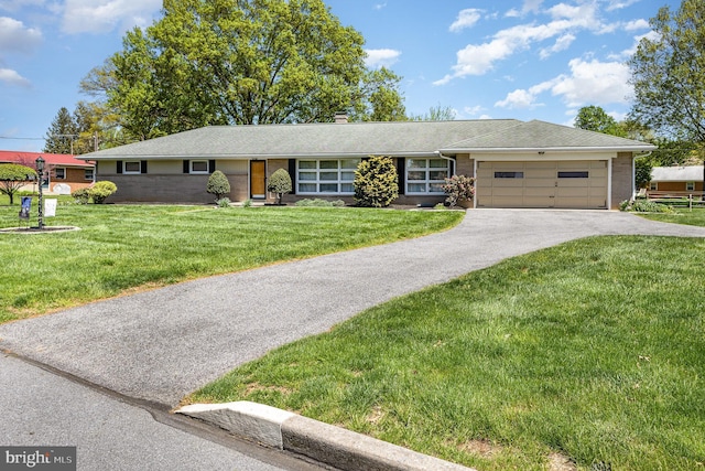 ranch-style house featuring a garage, aphalt driveway, a front yard, a chimney, and brick siding