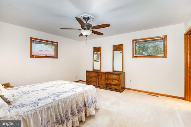 carpeted bedroom featuring baseboards, multiple windows, ceiling fan, and visible vents