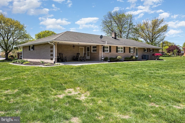 back of house featuring a lawn, a chimney, a patio area, and central air condition unit