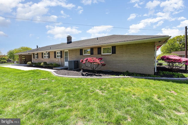 rear view of property with a lawn, brick siding, cooling unit, and a chimney